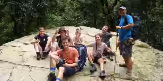 trekkers resting on rocky forest ledge during mountain trail in nepal Trekkers resting on rocky forest ledge during mountain trail in nepal