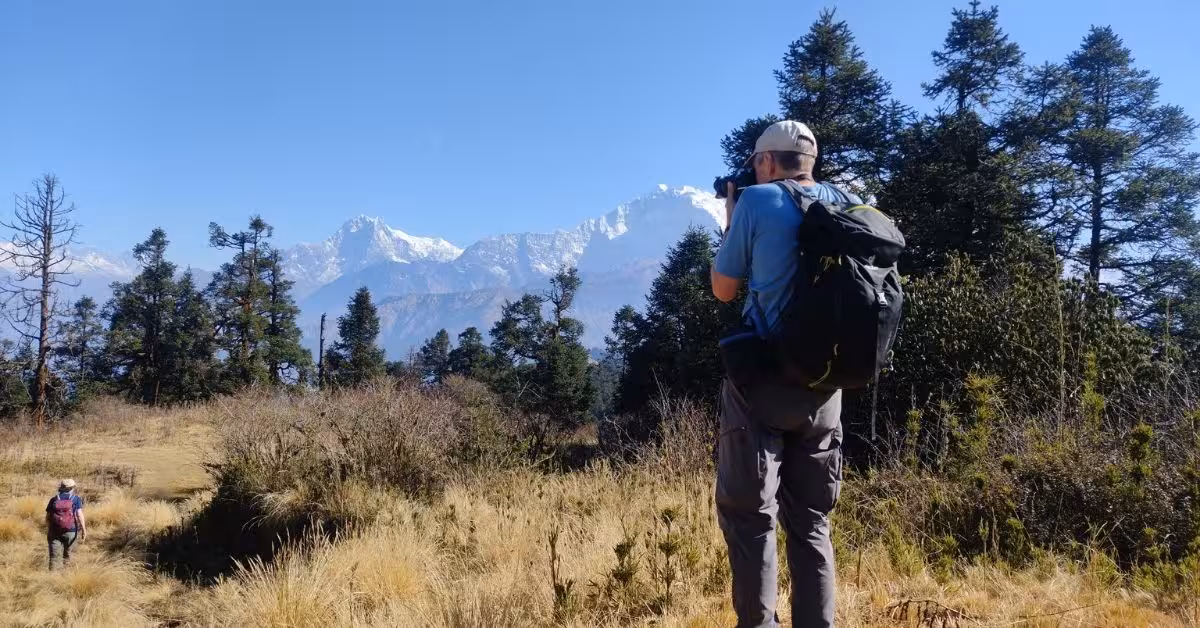Trekker capturing scenic view with camera on trail