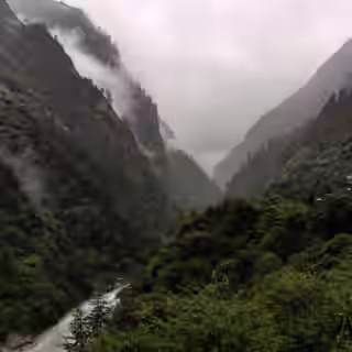 Misty river valley surrounded by lush green hills on the Tsum Valley trek