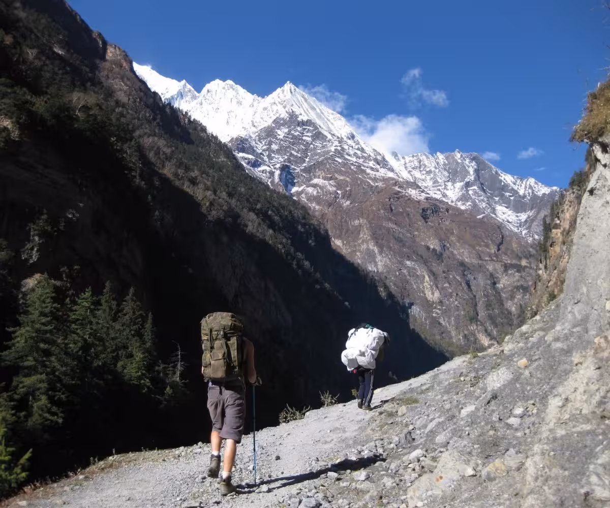 Trekker and porter climbing rocky Manaslu trail