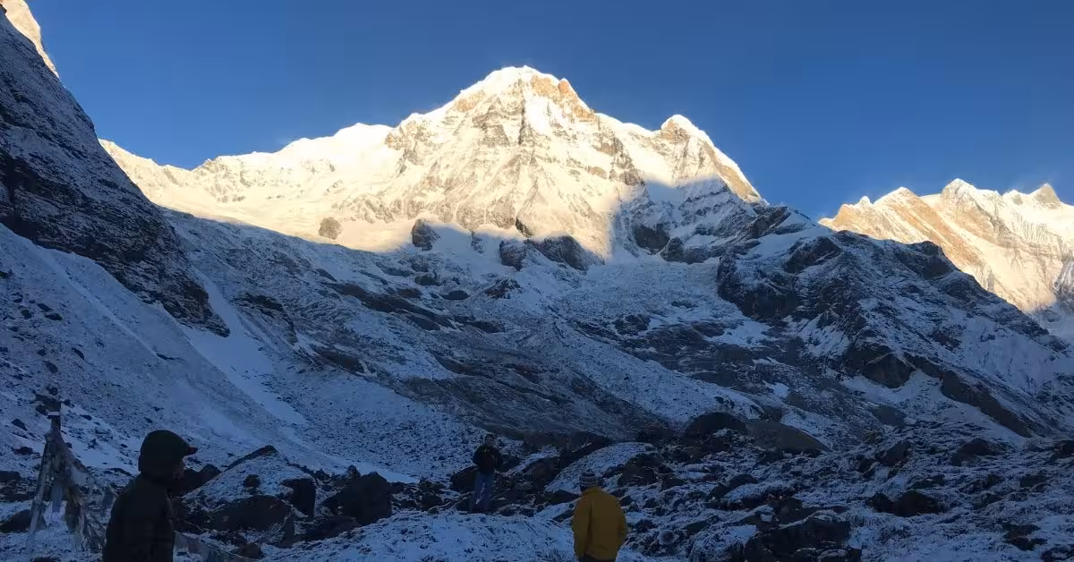 View of ABC lodges and prayer flags against dramatic Himalayan peaks in autumn